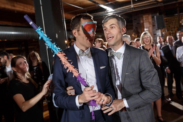 Chicago Gay Wedding Photography of gay grooms with a rainbow pinata at Salvage One