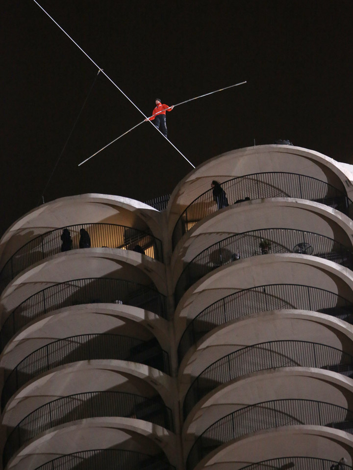 Daredevil Nik Wallenda starts his walk along a tightrope between two skyscrapers suspended 500 feet (152.4 meters) above the Chicago River as a plane flys past in Chicago, Illinois, November 2, 2014. REUTERS/John Gress