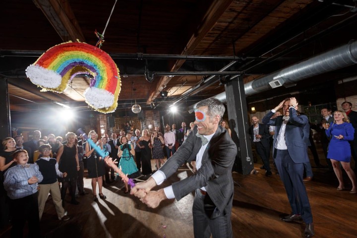 Chicago Gay Wedding Photography of gay grooms with a rainbow pinata at Salvage One
