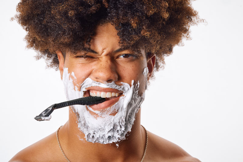 fun lifestyle image with a male model on a whote background with shaving foam and a razor