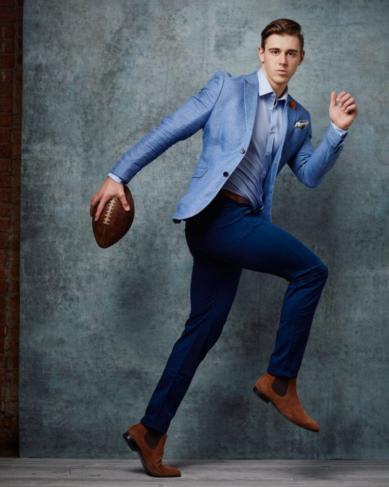 A Chicago male model poses in a suit with a football for a GQ style fashion photoshoot by photographer John Gress
