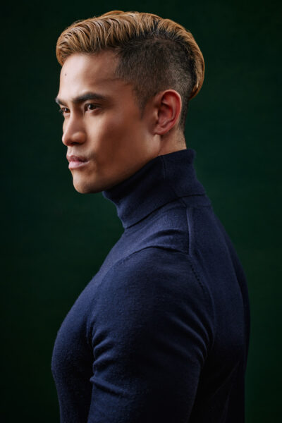 An asian male model poses for Chicago headshot photographer in front of a green background.