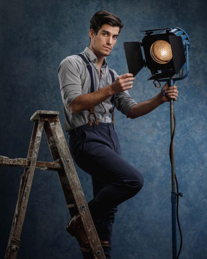 male model posing on a ladder with movie set props