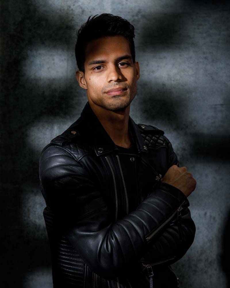 male model headshot on dark background with shadows on face