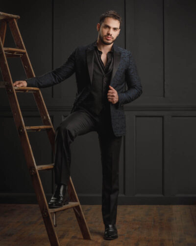 male model in black suit posed on ladder for chicago modeling portfolio