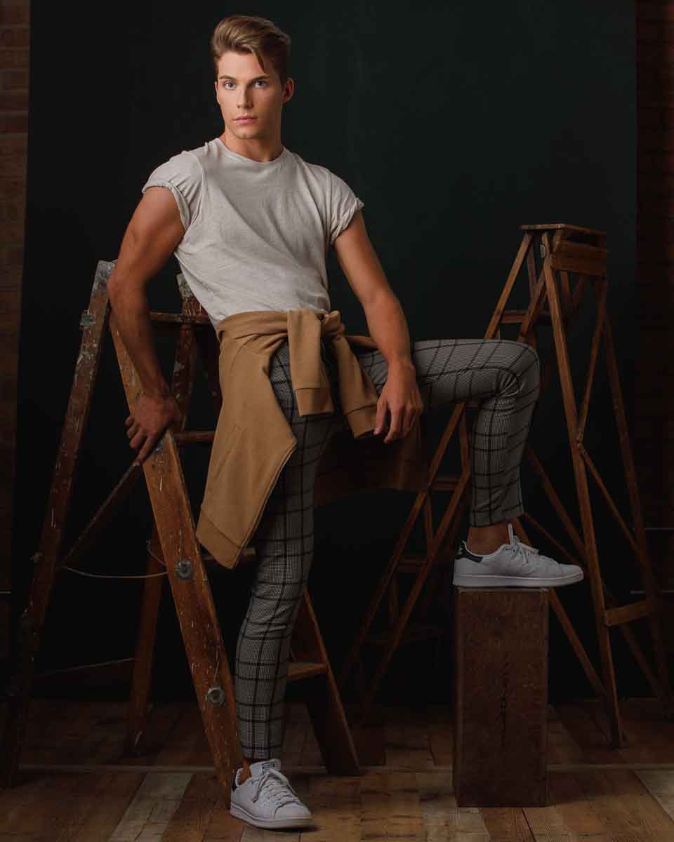 Full body portrait of Christian standing with white tennis shoes, plaid pants, and a tan jacket by the best model headshot services in Chicago