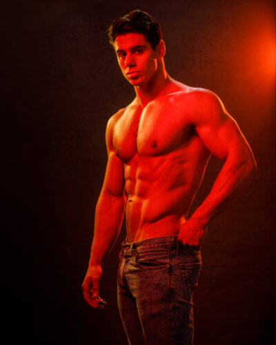Dramatic high contrast red lighting showcasing Nick's muscular physique in a fitness model photography session in Chicago