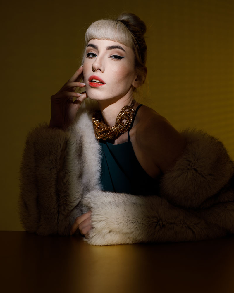Dramatically lit portrait of Gabriella in fur coat against yellow background by a freelance model photographer in Chicago