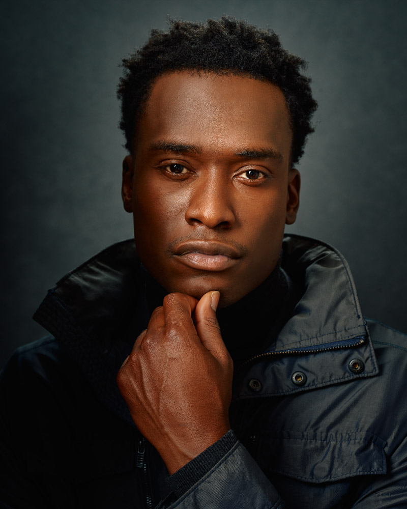 Headshot of Justin in a gray turtleneck and lighter gray coat