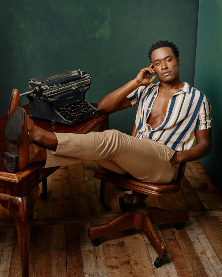 Justin in casual wear with feet up on a desk, next to a typewriter for hiss model digital portfolio in Chicago
