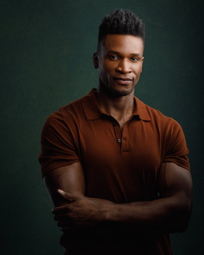 Casual yet powerful portrait of Chaun in a rusty brown polo shirt, emphasizing his muscular arms as a fitness model in Chicago