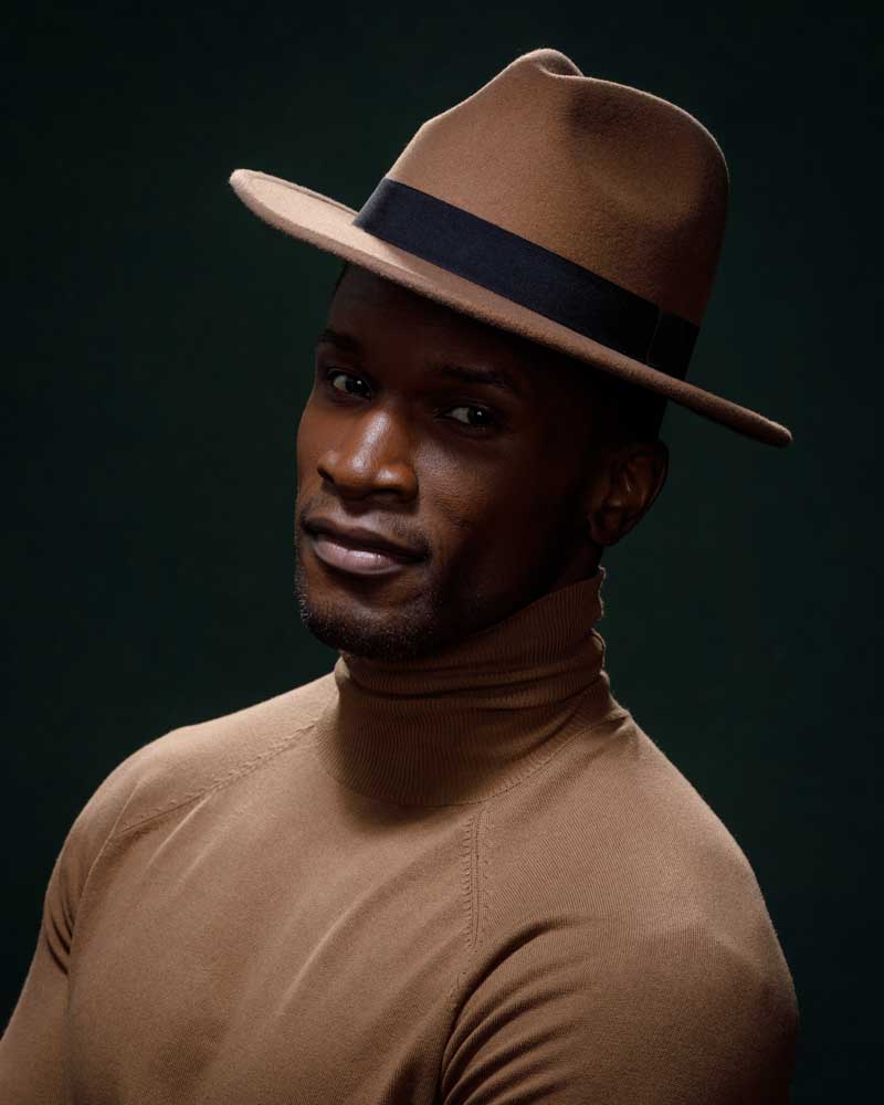 Sophisticated portrait of Chaun in brown turtleneck and hat, showcasing artistic shadow play by a fitness photographer in Chicago