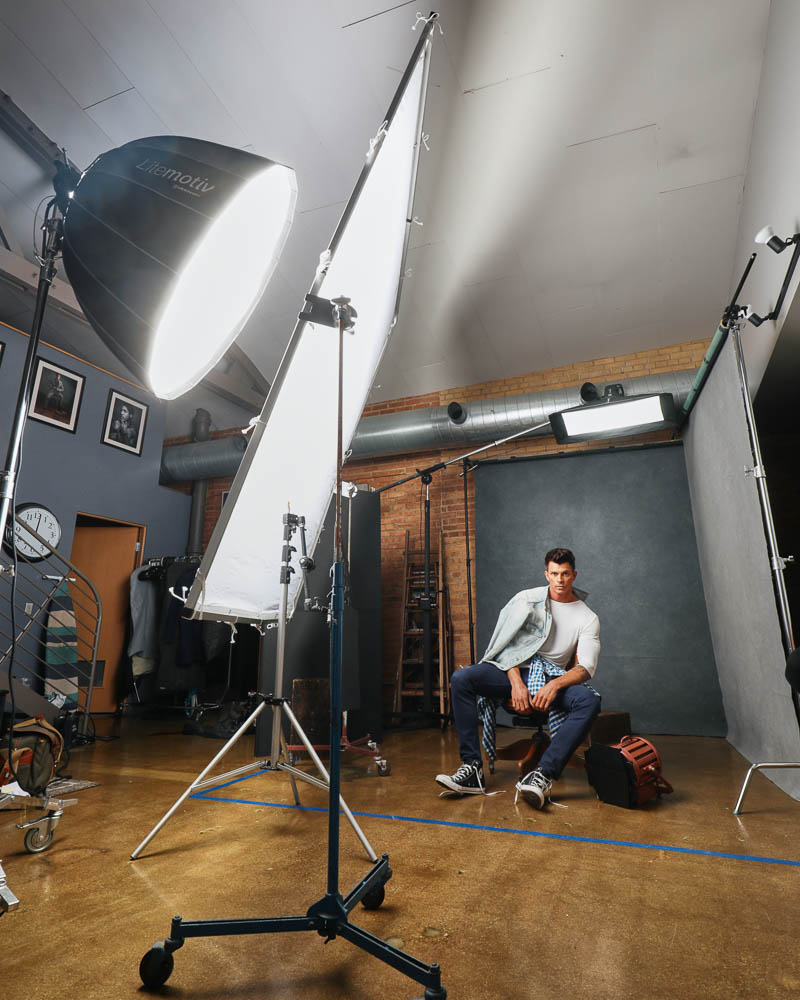 Kenny, dressed in casual attire, sits in an antique wooden chair during a photoshoot. This image reflects the relaxed yet professional atmosphere of John Gress Photography in Chicago.