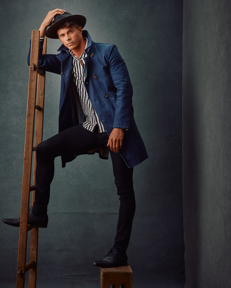Kenny, in casual clothing, leans on an antique wooden ladder. This image highlights the diverse looks captured in professional model photoshoots by John Gress Photography in Chicago.