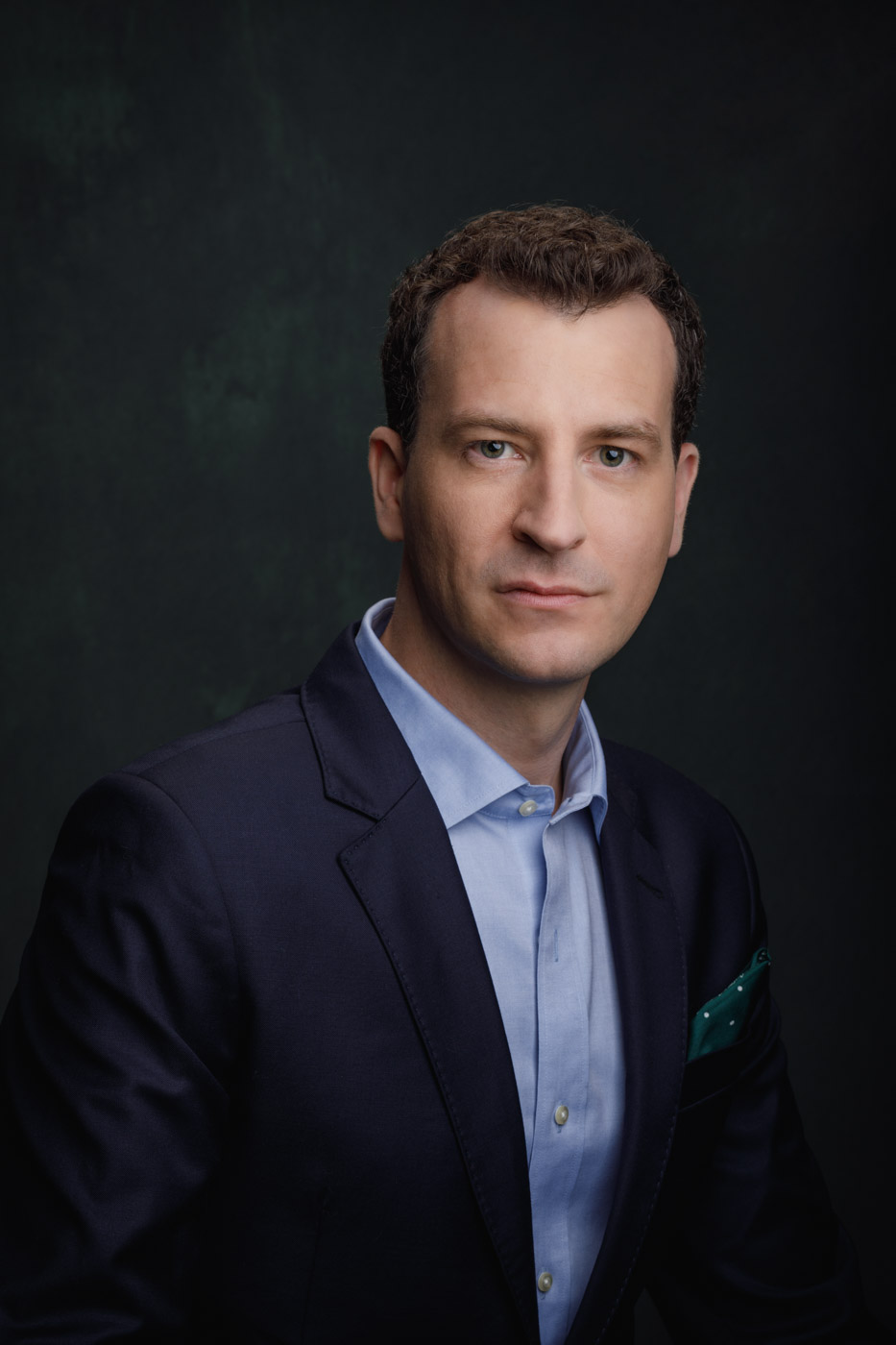 acting head shot Chicago, close-up of Stephen in blue suit jacket against green canvas backdrop