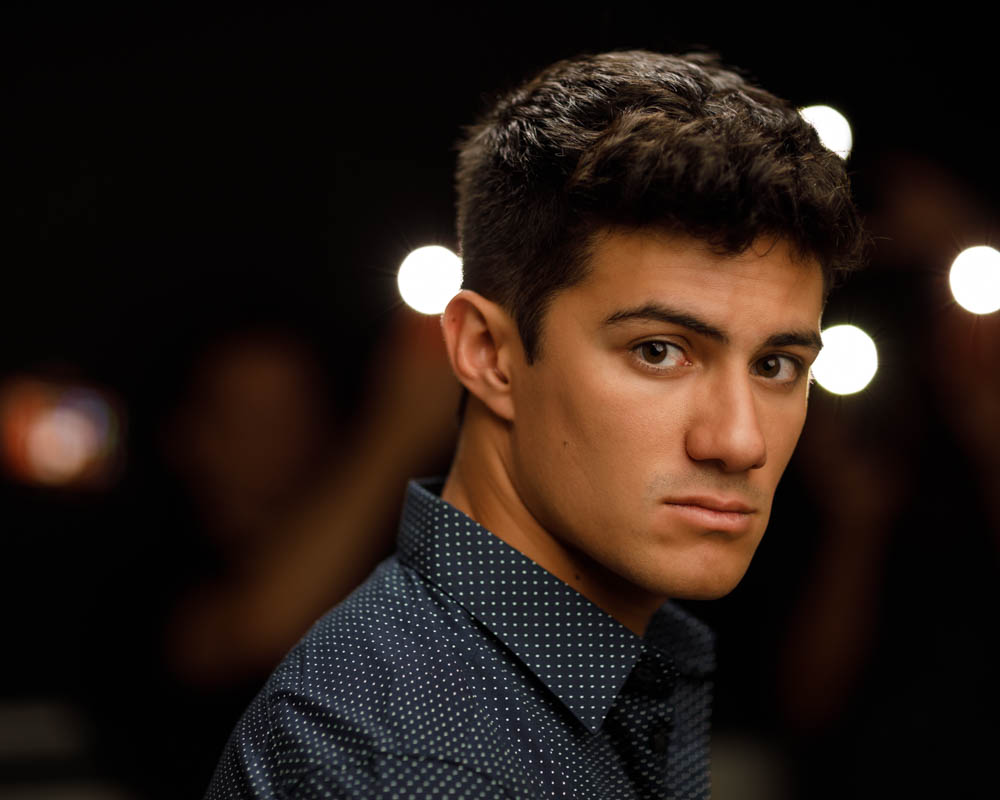 Horizontal shallow depth of field headshot Chicago of Kainoa with twinkling white lights in the background, simulating a cinematic scene