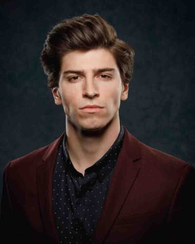 Noah in a high contrast color headshot, wearing a maroon suit jacket, ideal for grabbing a casting director’s attention.