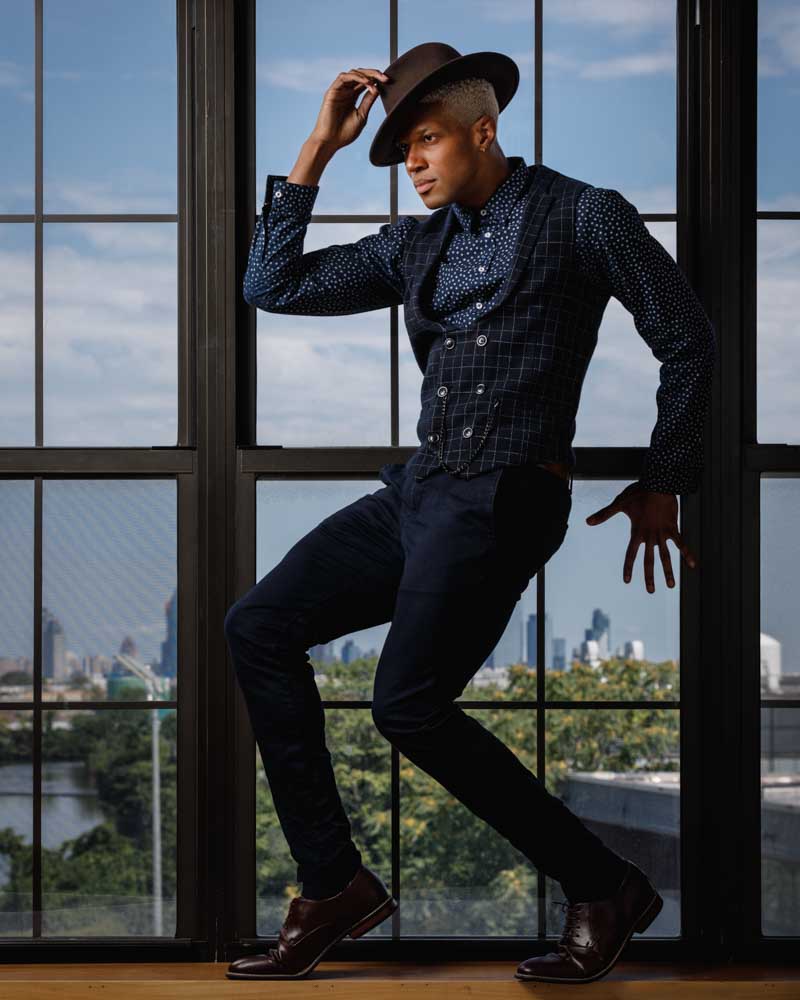 Jaquez demonstrates his versatility in a dynamic dance pose, dressed elegantly in a blue outfit complete with a dress shirt, vest, and hat