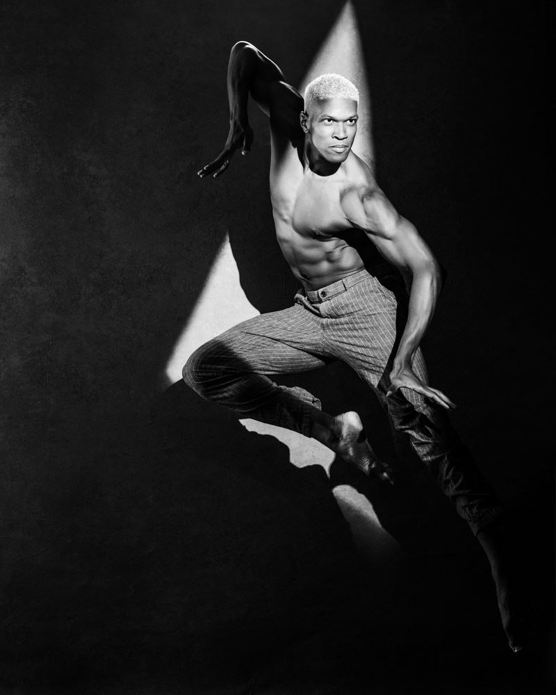 Capturing Jaquez's dynamic movement, this high-contrast black and white image showcases his skill as a dancer in a striking shaft of light