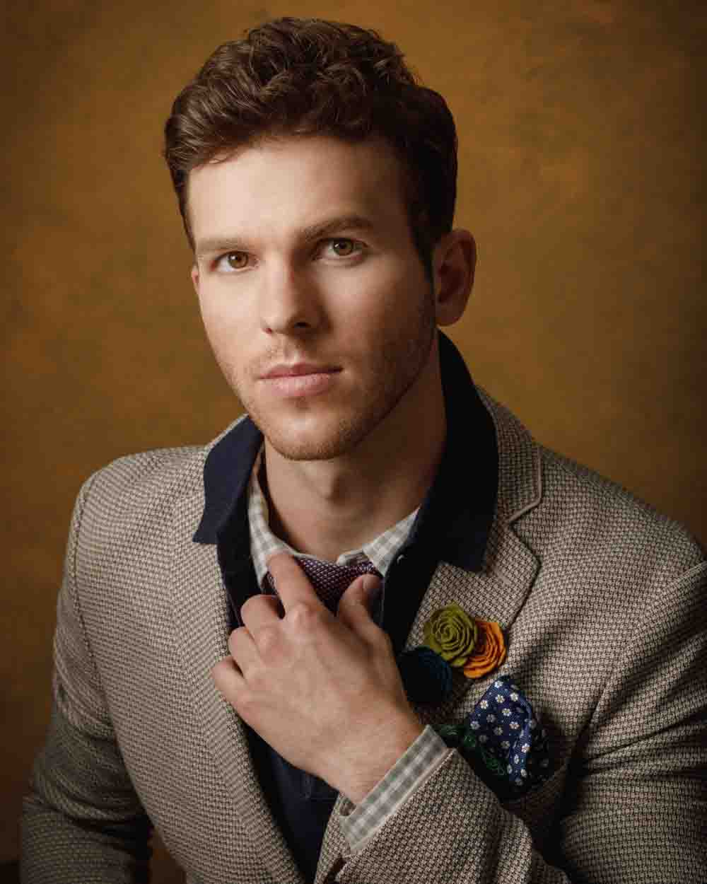 Headshot of Connor in a beige suit jacket