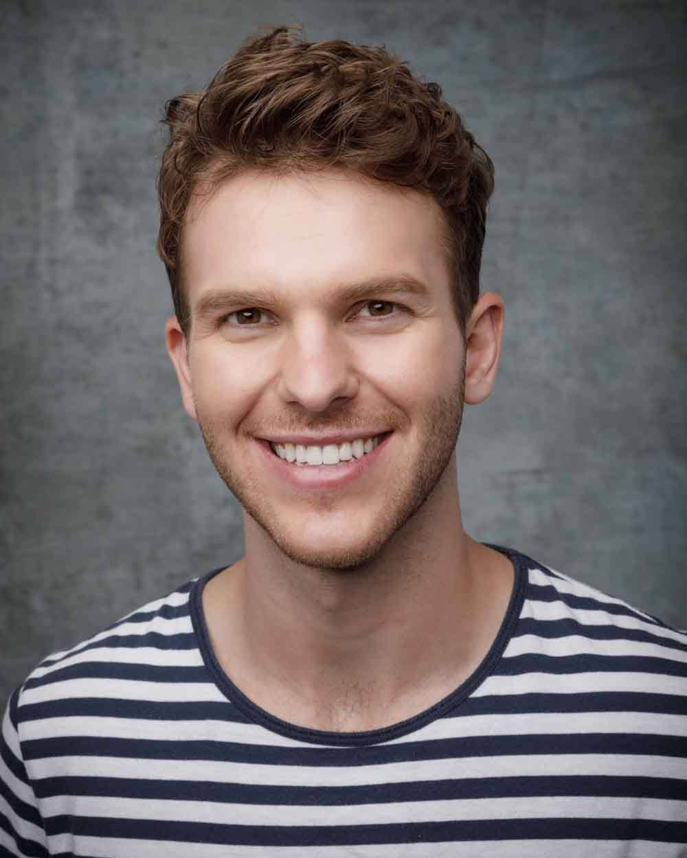 Smiling headshot of Connor in a stripped t-shirt