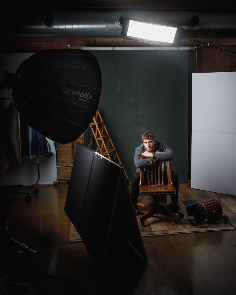 Behind the scenes of Jay's photo shoot with a vintage movie light and green backdrop, highlighting the production quality.