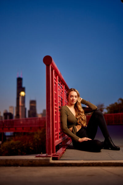 Hannah seated along the Chicago River at Tom Ping Park, wearing a stylish dress that complements the Chicago skyline at twilight