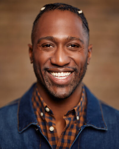 Chicago acting headshots of Preston with a genuine smile, wearing a denim jacket and checkered shirt.