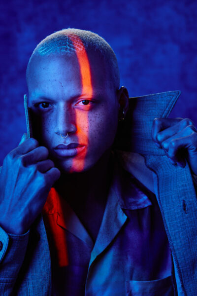 This is a headshot of Christopher bathed in blue light with a stripe of red light lighting one eye taken by a top Chicago photographer foe models