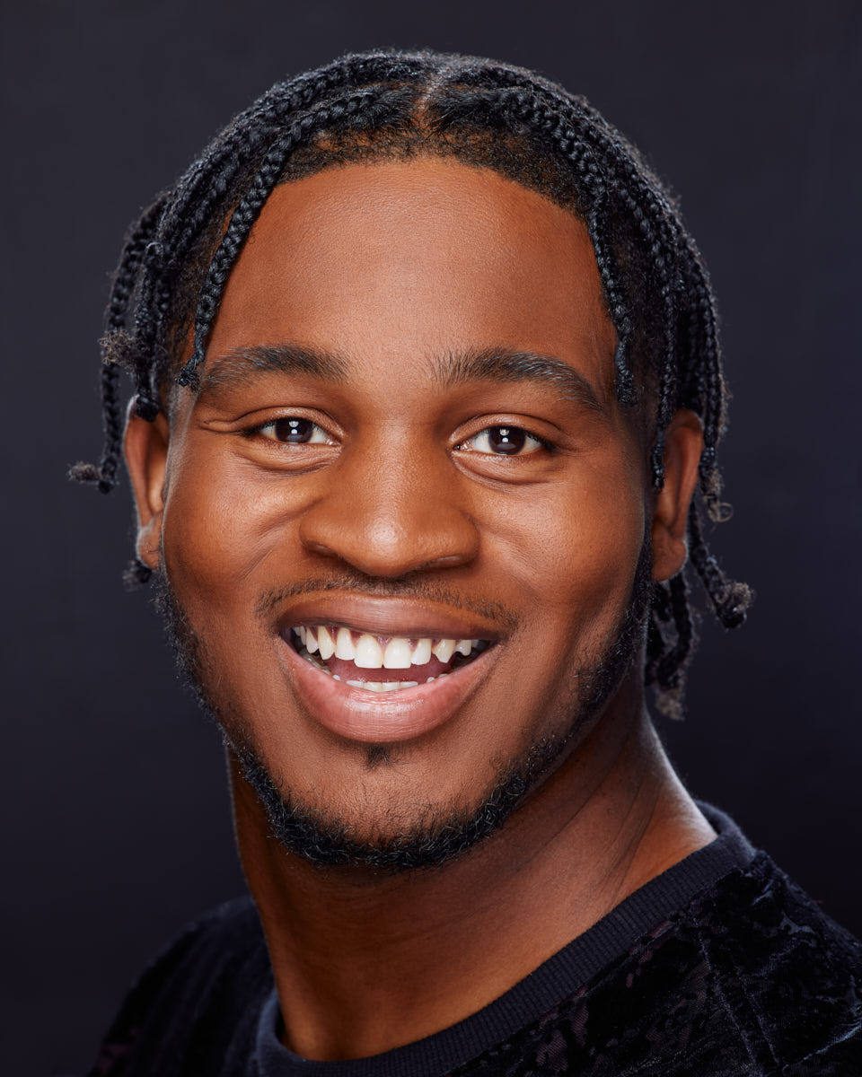 Josiah's friendly and engaging expression, with neatly styled braids and a dark top, perfect for actor headshots in Chicago.