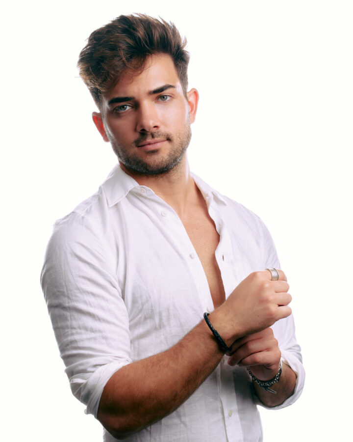 Eric is in a white button-down shirt, looking relaxed and confident, with his hands clasped, against a plain white background.