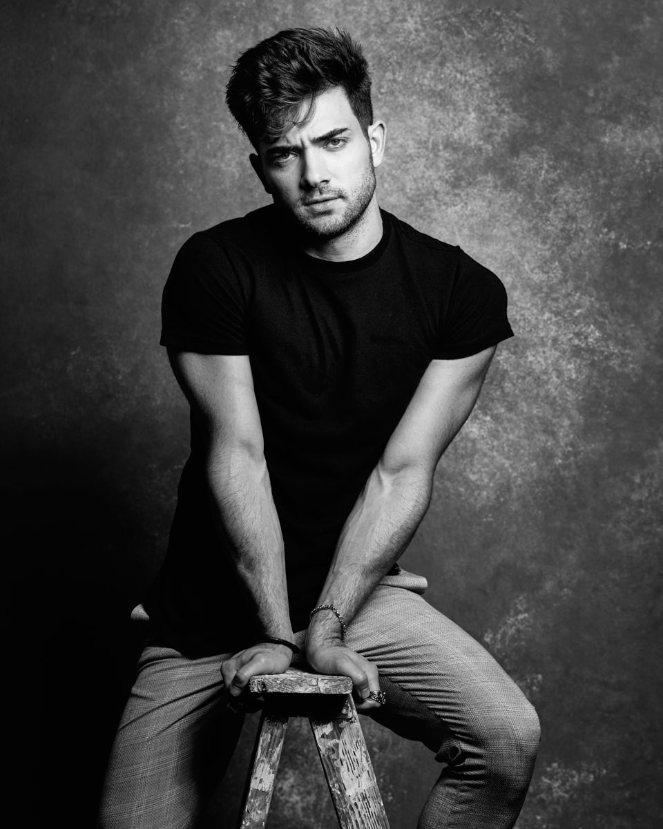 Chicago editorial lookbook photographer -A dramatic black-and-white portrait of Eric in a black t-shirt and gray pants, with an intense, serious expression, highlighting his strong features.