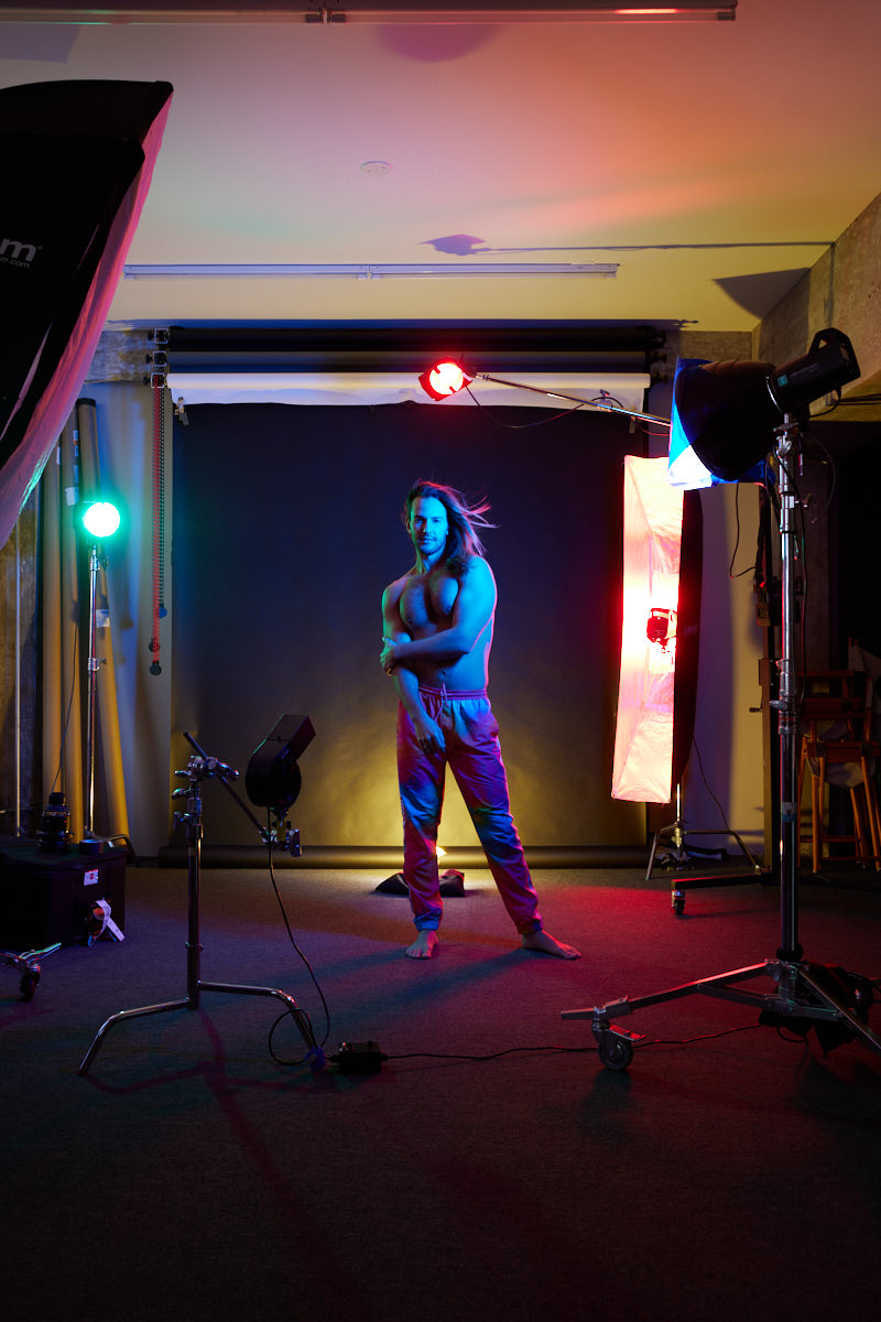 A behind-the-scenes image of Glaydson Jr. walking in the studio, with lighting equipment set up around him, capturing the dynamic atmosphere of the photoshoot