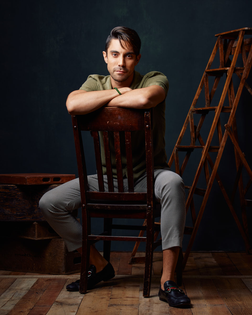 Male Model Headshots in Chicago-Similar setup as Image 2, with Daniel leaning on the chair in a green shirt and checkered pants, exuding a relaxed yet stylish vibe.
