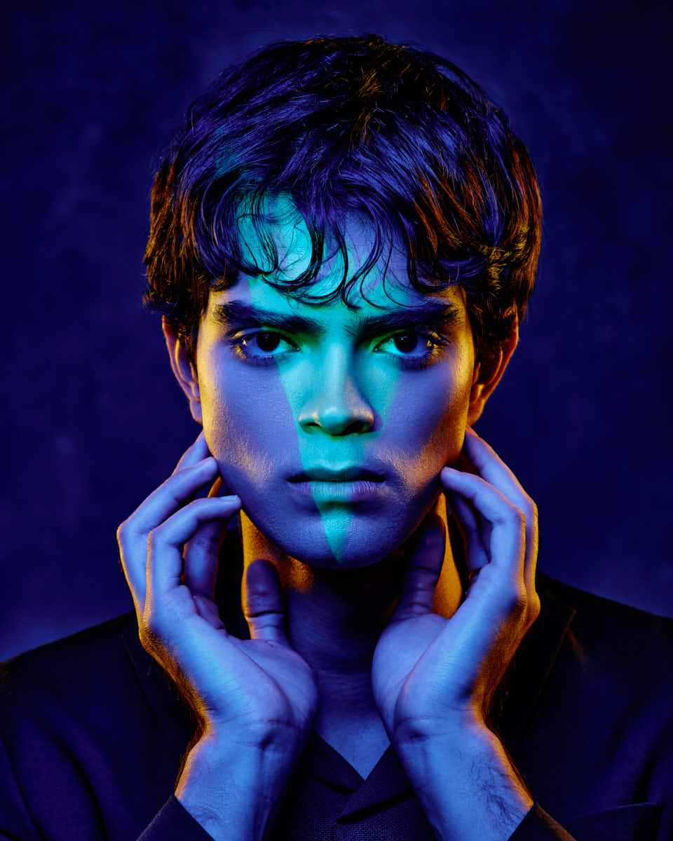 A highly stylized shot using colored gels (blue and green) to create a dramatic split-light effect on Enrique’s face.