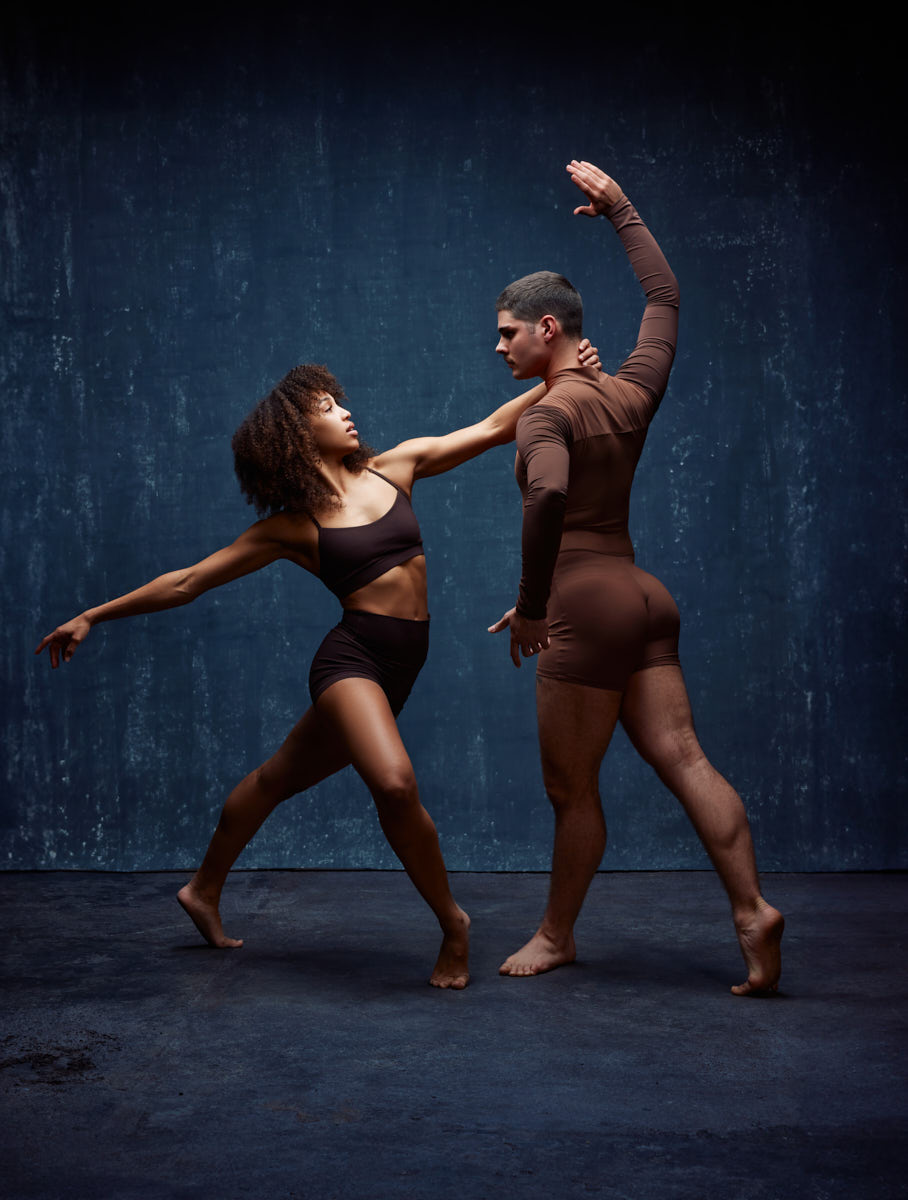Modern Dance photographer Chicago-Mya and Zach engage in an intense dance interaction, with Mya in a deep lunge facing Zach, who appears to be turning away. Mya’s body language suggests a sense of pushing or pulling.