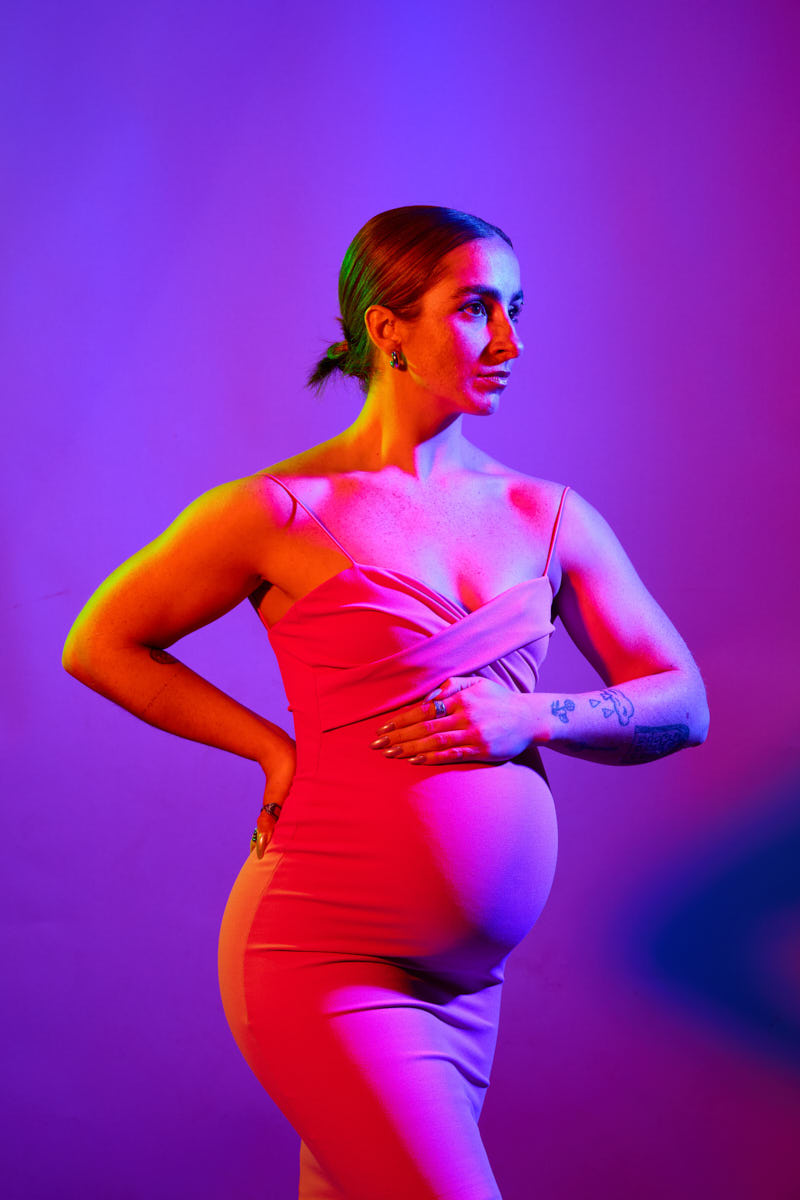 Chicago Maternity Photographer-Dramatic full-body maternity portrait of a woman in a flowing black dress, arms gently posed and expression serene.