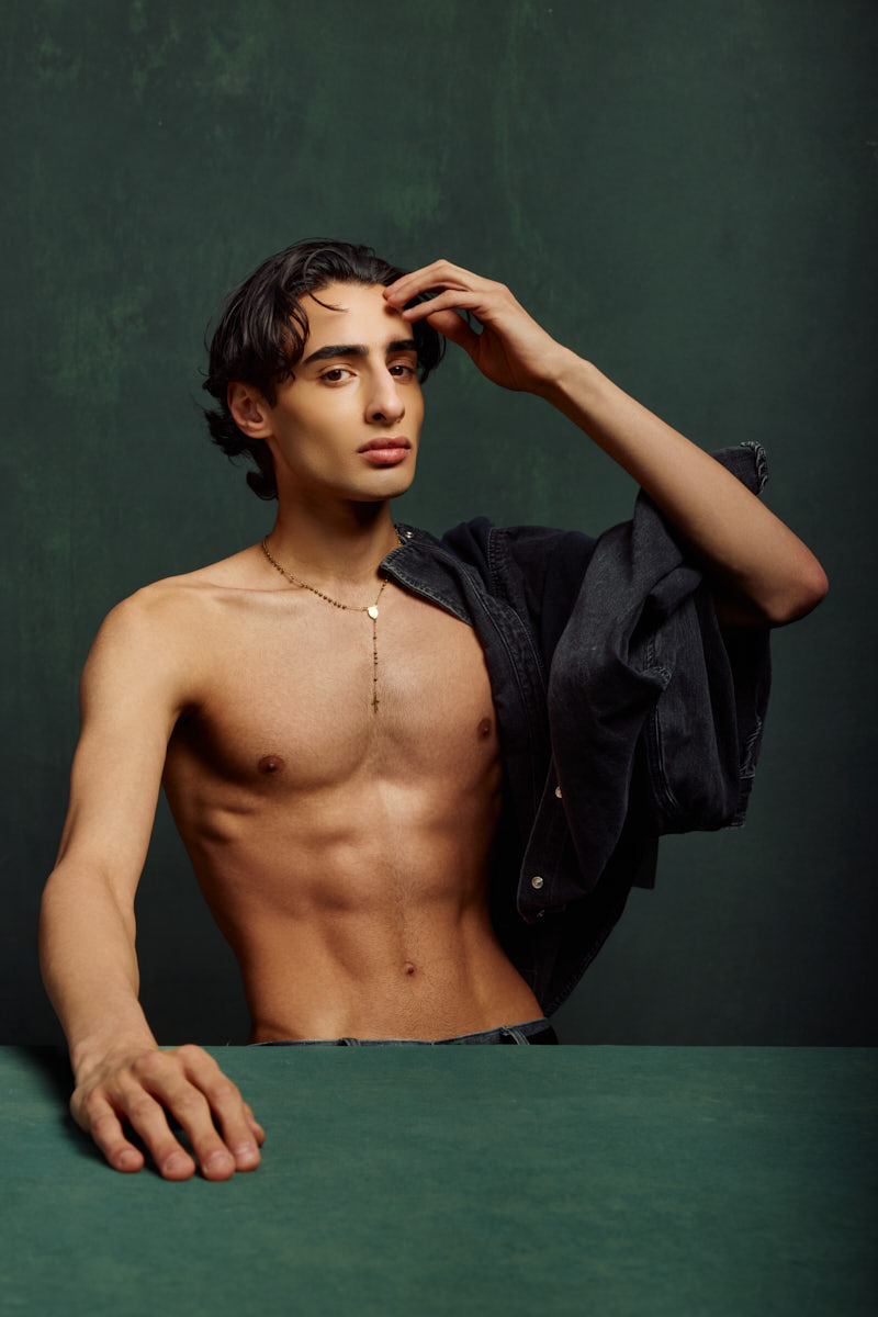 Giorgio posing with a denim jacket draped over one shoulder in a dramatic portrait for a Male Fashion model portfolio Chicago.