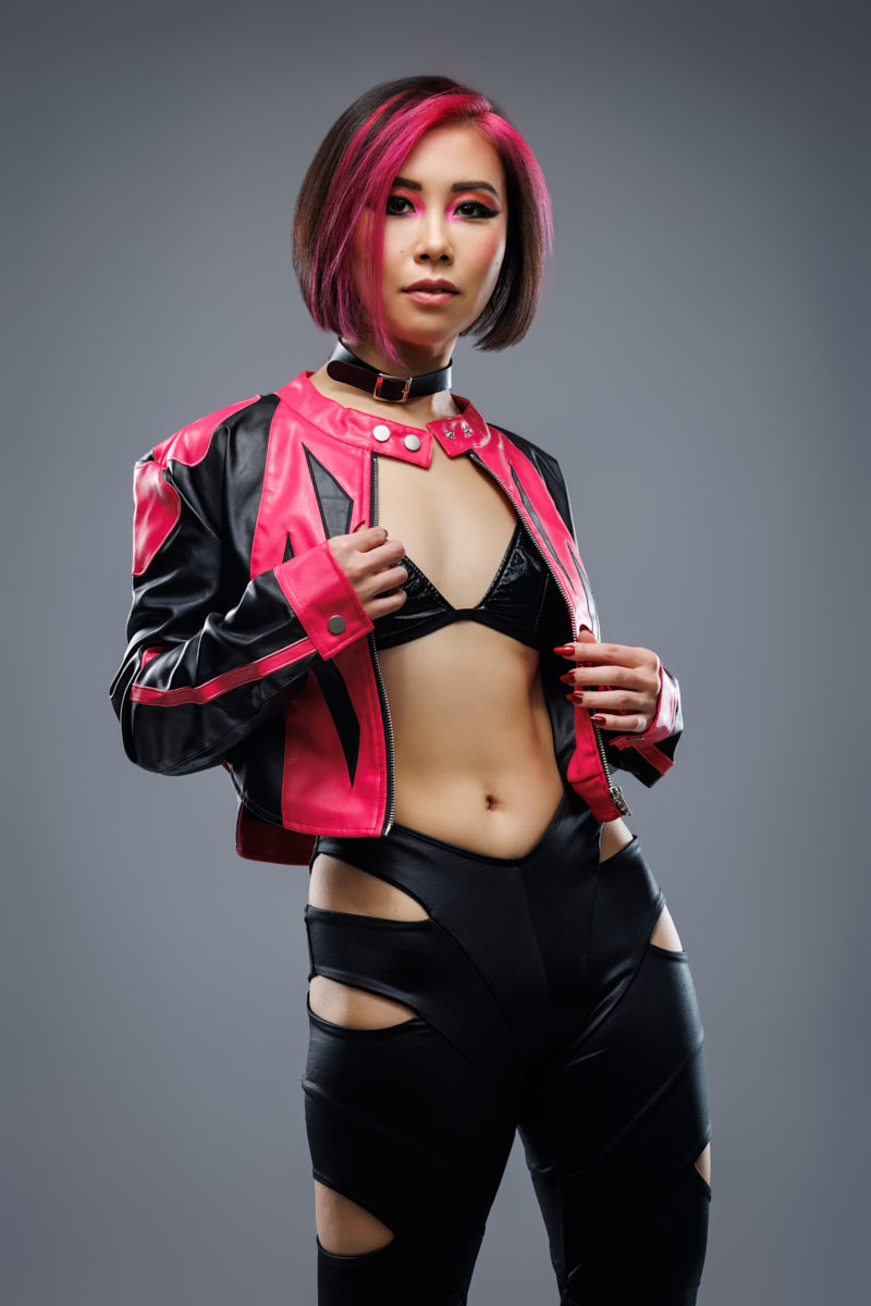 Music marketing photography Chicago portrait of Tianqing wearing a pink and black jacket against gray