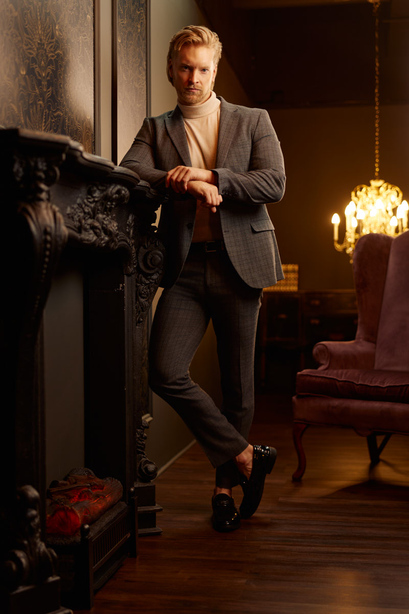 Nick poses beside an ornate fireplace during an editorial portrait session in Chicago