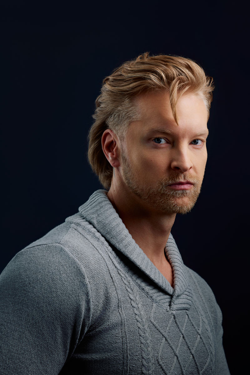 Editorial headshot photographer in Chicago photographs Nick in a textured gray sweater against a dark background