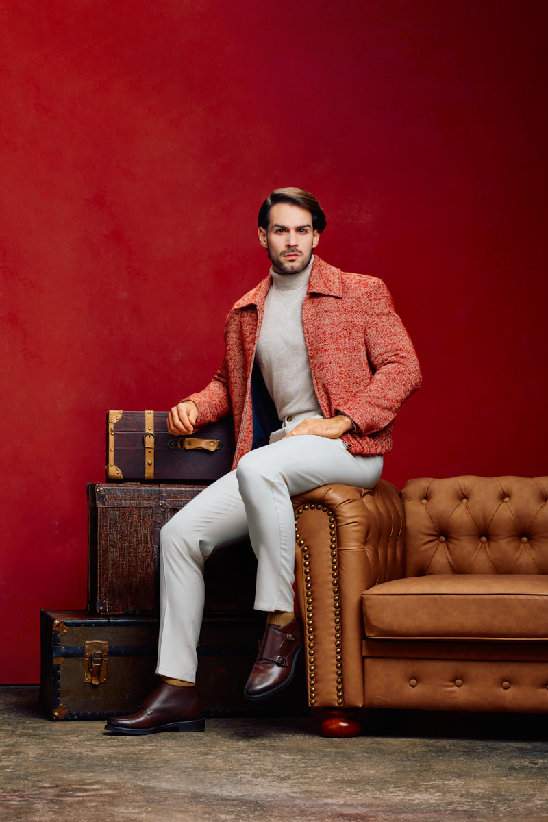 Athletic model photographer Chicago fashion portrait of Jamie in a textured red jacket beside vintage luggage and a leather sofa.