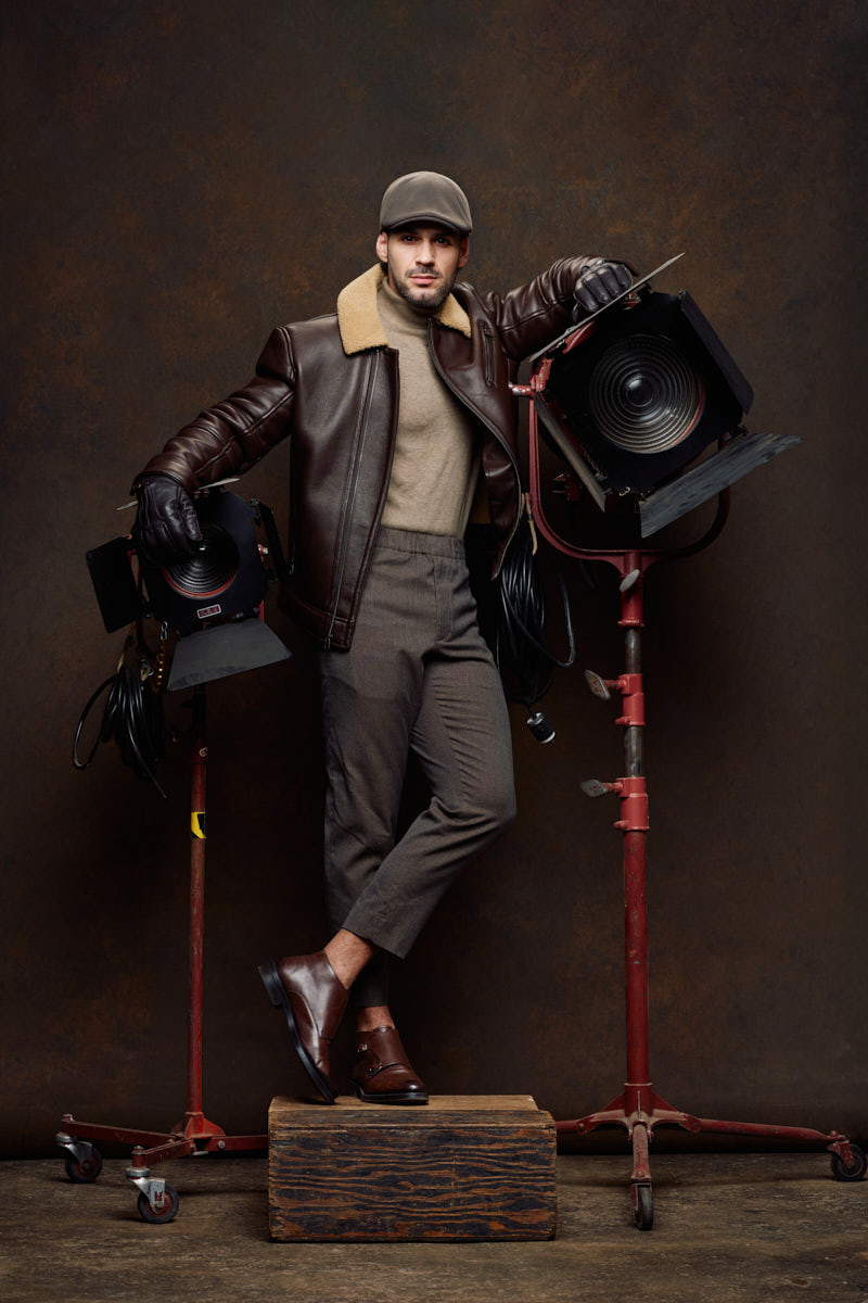 Athletic model photographer Chicago portrait of Jamie in a leather aviator jacket posing between vintage film lights.